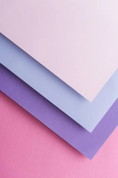 Top view of blue, white and purple sheets of paper on pink background with copy space — Stock Photo