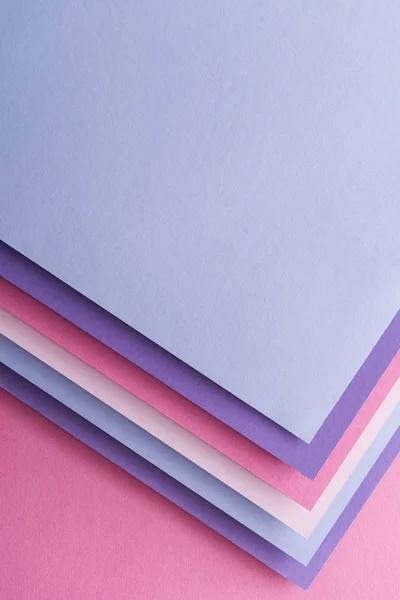 Top view of blue, white, pink and purple sheets of paper on pink background with copy space — Stock Photo