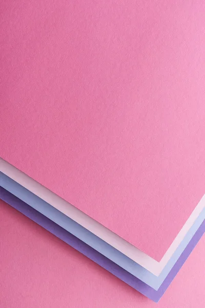 Top view of blue, white, pink and purple sheets of paper on pink background — Stock Photo