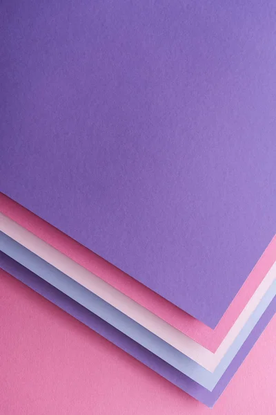 Вид сверху на пустые голубые, белые, розовые и фиолетовые листы бумаги на розовом фоне — стоковое фото