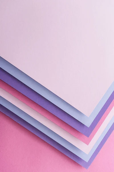 Vista superior de hojas de papel en blanco azul, blanco, rosa y púrpura sobre fondo rosa - foto de stock