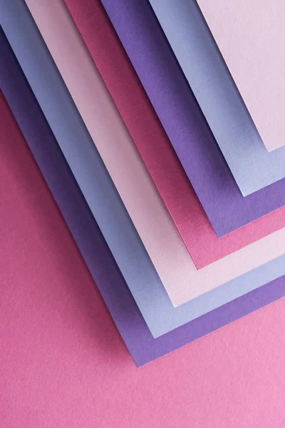 Top view of empty blue, white, pink and purple sheets of paper on pink background with copy space — Stock Photo