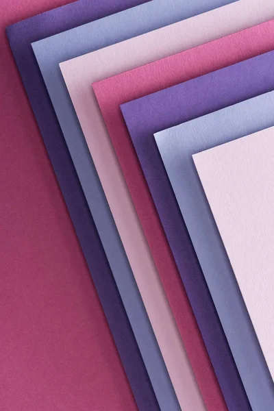 Top view of blue, white, pink and purple sheets of paper on pink background — Stock Photo