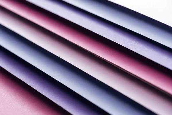 Hojas vacías de papel azul, blanco, rosa y púrpura sobre fondo rosa - foto de stock
