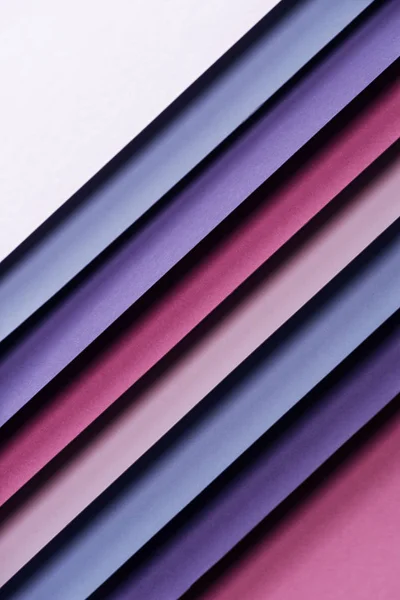 Верхний вид чистых голубых, белых, бордовых, розовых и фиолетовых листов бумаги на розовом фоне — стоковое фото