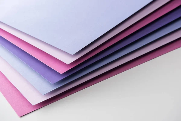 Hojas de papel en blanco azul, blanco, rosa y púrpura sobre fondo blanco - foto de stock