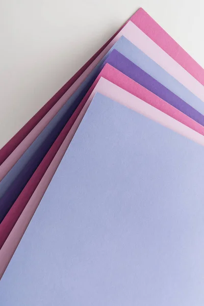 Vista dall'alto di fogli di carta blu, bianchi, rosa e viola vuoti su sfondo bianco — Foto stock