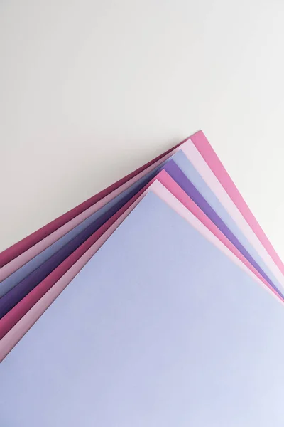 Вид зверху на сині, білі, рожеві та фіолетові листи паперу на білому тлі — стокове фото
