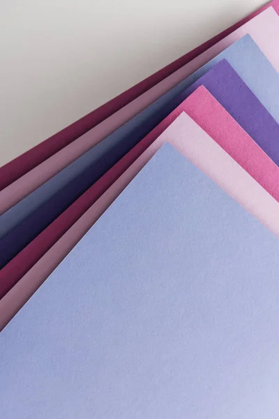 Vista superior de folhas de papel azul, branco, rosa e roxo em branco sobre fundo branco — Fotografia de Stock