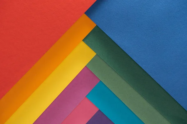 Вид зверху барвистих червоних, бордових, синіх, помаранчевих, зелених, жовтих, рожевих і фіолетових листів паперу — стокове фото