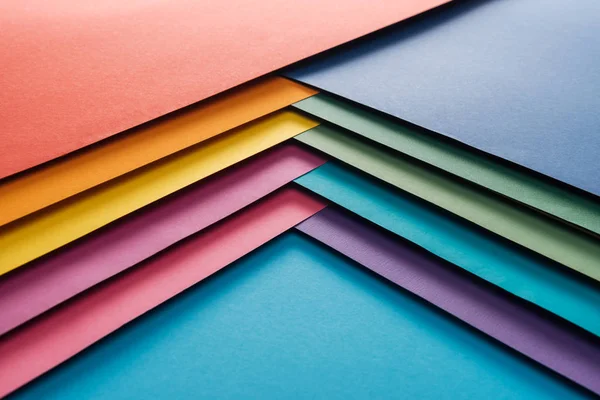 Blue, orange, green, burgundy, yellow, pink and purple sheets of paper on blue background — Stock Photo