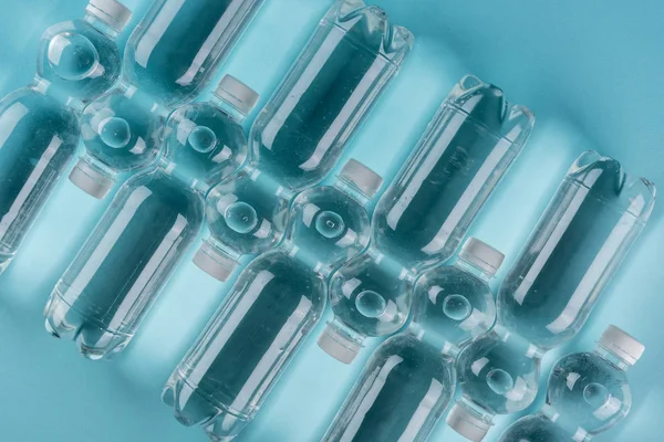 Vue du dessus des bouteilles d'arrosage en plastique transparent sur fond turquoise — Photo de stock