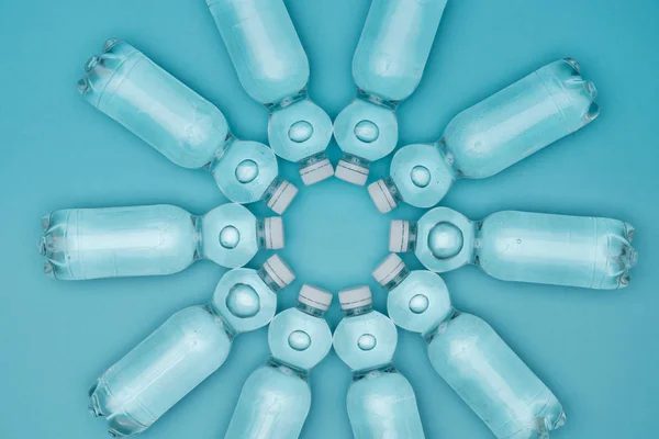 Vista dall'alto di bottiglie d'acqua di plastica con bolle isolate su turchese — Foto stock