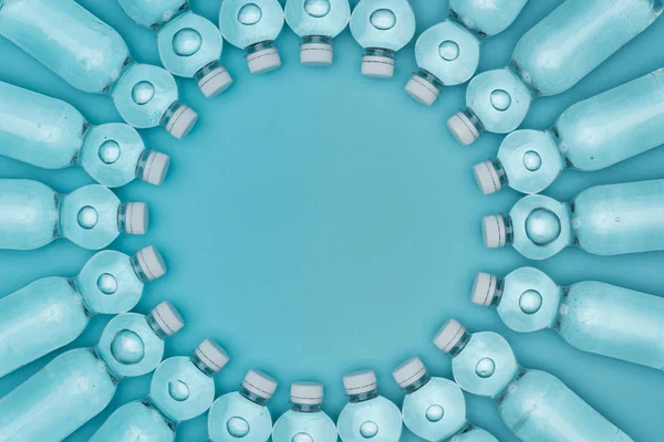 Vue de dessus du cadre rond en bouteilles d'eau en plastique isolées sur turquoise avec espace de copie — Photo de stock