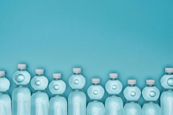 Top view of plastic water bottles isolated on turquoise with copy space — Stock Photo