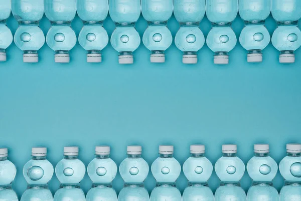 Vue de dessus du cadre en bouteilles d'eau en plastique isolées sur turquoise avec espace de copie — Photo de stock