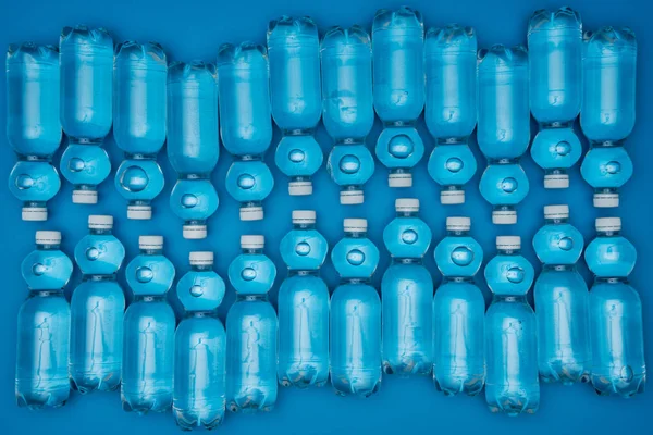 Vista superior de botellas de agua de plástico aisladas en azul - foto de stock