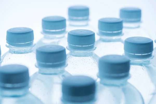 Foco seletivo de garrafas de água com tampas em fundo branco — Fotografia de Stock