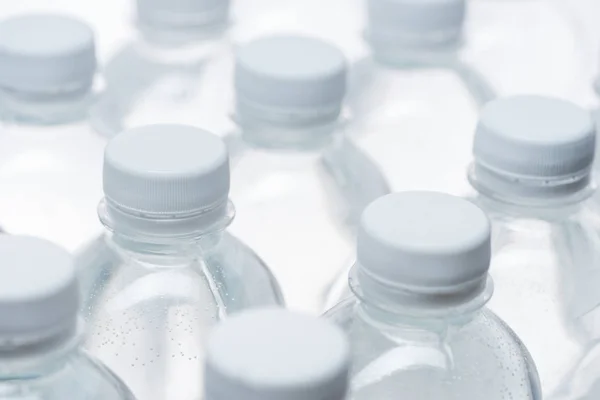 Messa a fuoco selettiva di bottiglie d'acqua con tappi su sfondo bianco — Foto stock