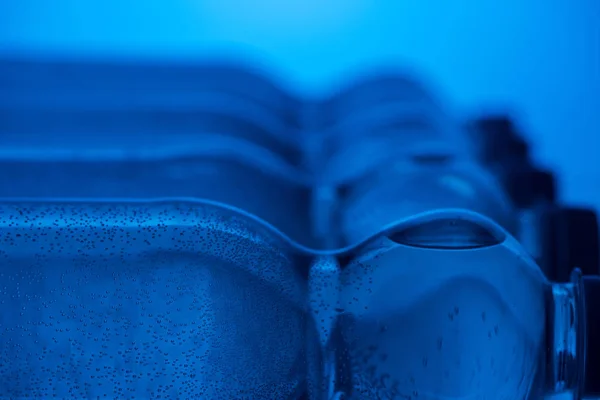 Close-up de garrafas de água de plástico com bolhas e espaço de cópia no fundo azul — Fotografia de Stock