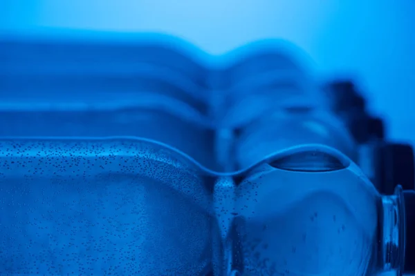 Close up of plastic water bottles with bubbles and copy space on blue background — Stock Photo