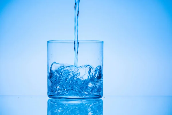 Image tonique de l'eau versant dans le verre sur fond bleu avec espace de copie — Photo de stock