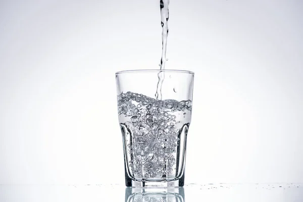 Background of water pouring in glass on white with backlit and copy space — Stock Photo