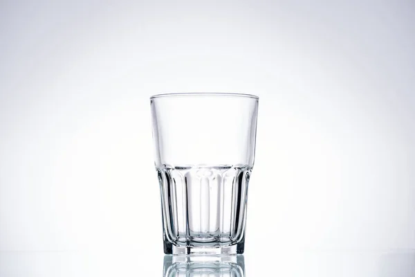 Leeres Glas auf weißem Hintergrund mit Hintergrundbeleuchtung und Kopierraum — Stockfoto