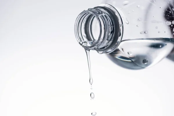 Goteo de agua de la botella de plástico aislado en blanco con espacio de copia - foto de stock