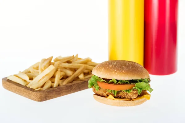 Tasty chicken burger near french fries and bottles isolated on white — Stock Photo