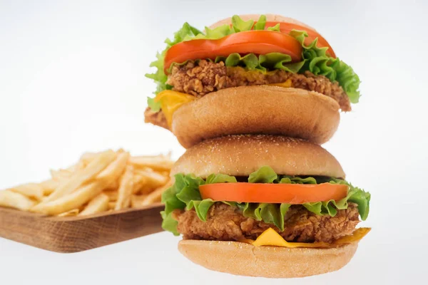 Foco selectivo de sabrosas hamburguesas de pollo cerca de papas fritas aisladas en blanco - foto de stock