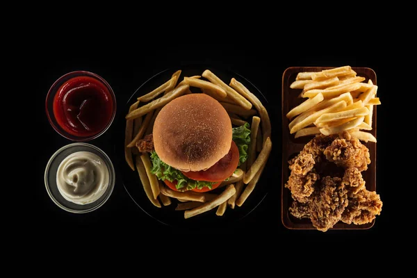 Вид сверху на вкусную нездоровую пищу, изолированную на черном — стоковое фото