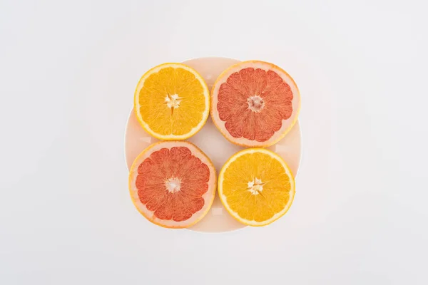Vista superior de naranjas en rodajas y pomelos en plato aislado en blanco - foto de stock