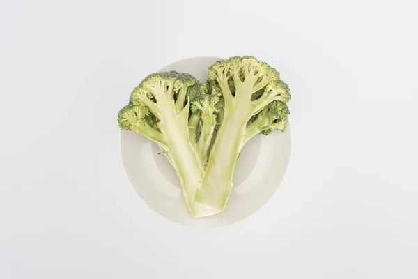 Top view of organic broccoli on plate isolated on white — Stock Photo