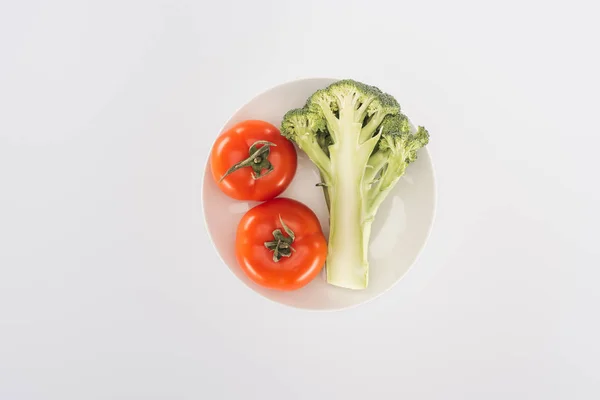 Vista superior de tomates vermelhos perto de brócolis orgânico na placa isolada em branco — Fotografia de Stock