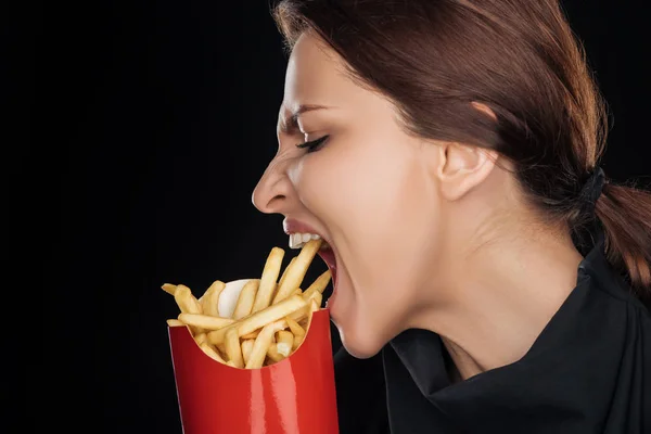 Emotionale Frau isst leckere Pommes auf schwarz isoliert — Stockfoto