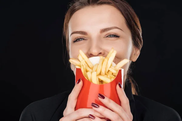 Femme couvrant visage avec des frites isolées sur noir — Photo de stock