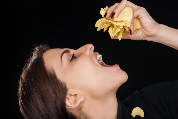 Bela mulher comer batatas fritas crocantes isolado no preto — Fotografia de Stock