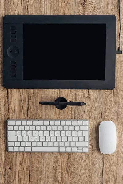 Вид сверху графического планшета, графической ручки, беспроводной клавиатуры компьютера и компьютерной мыши на деревянном столе — стоковое фото