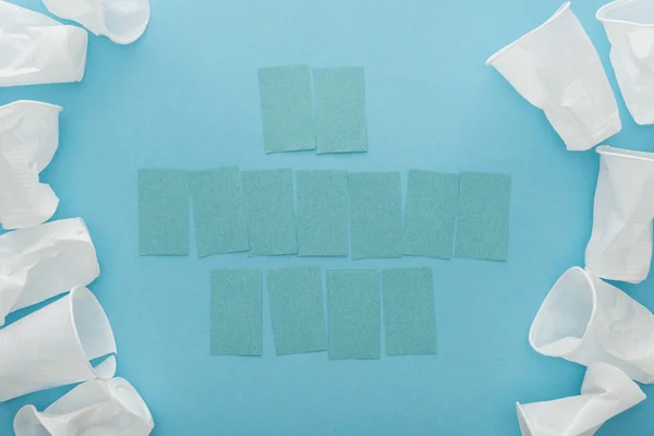 Top view of white plastic cups and blank sticky notes with copy space on blue background — Stock Photo