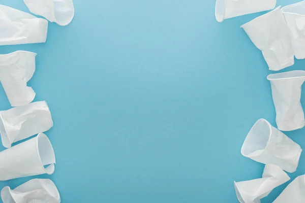 Top view of white and plastic cups on blue background with copy space — Stock Photo