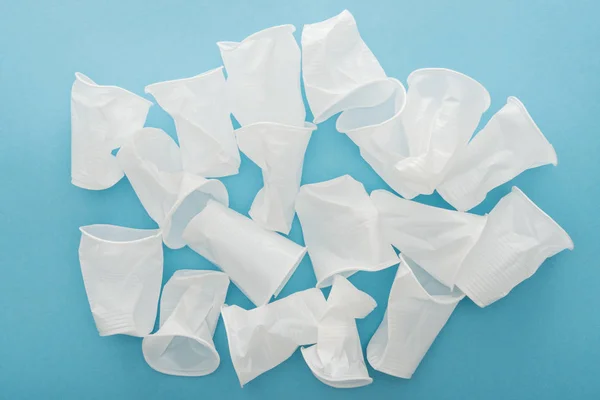 Top view of white and crumpled plastic cups on blue background — Stock Photo