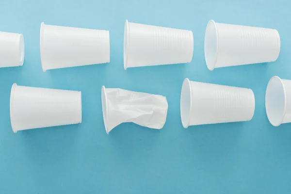 Вид зверху на білі зім'яті пластикові чашки на синьому фоні з копіювальним простором — стокове фото