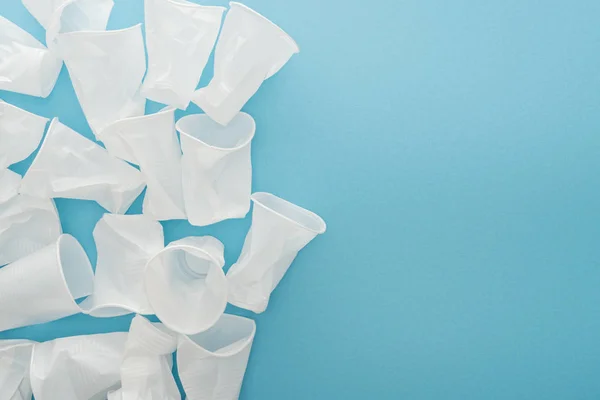 Top view of white and crumpled plastic cups on blue background with copy space — Stock Photo