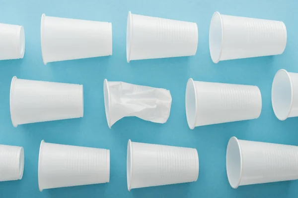 Вид зверху на білі та крихкі пластикові чашки на синьому фоні — стокове фото