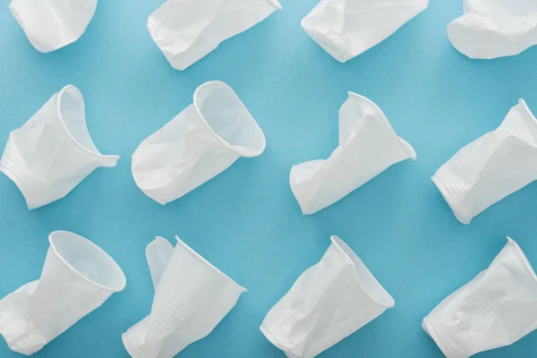 Draufsicht auf weiße und zerknüllte Plastikbecher auf blauem Hintergrund — Stockfoto