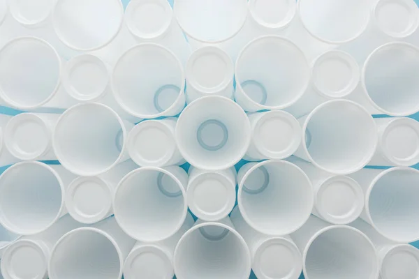Vista dall'alto di tazze bianche e di plastica su sfondo blu — Foto stock