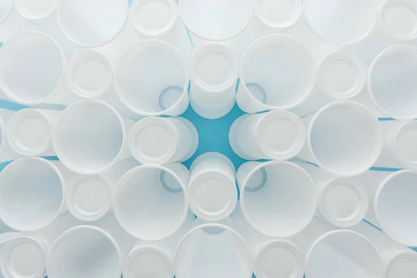 Вид зверху на білі пластикові чашки на синьому фоні з пробілом для копіювання — стокове фото