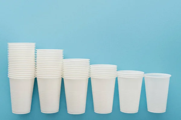 Flat lay with white plastic cups on blue background with copy space — Stock Photo