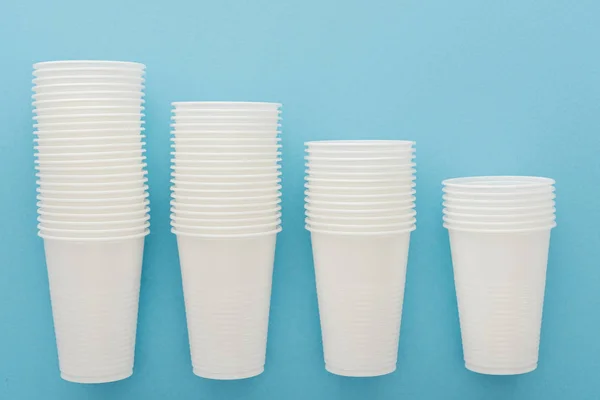 Flat lay with white plastic cups on blue background with copy space — Stock Photo